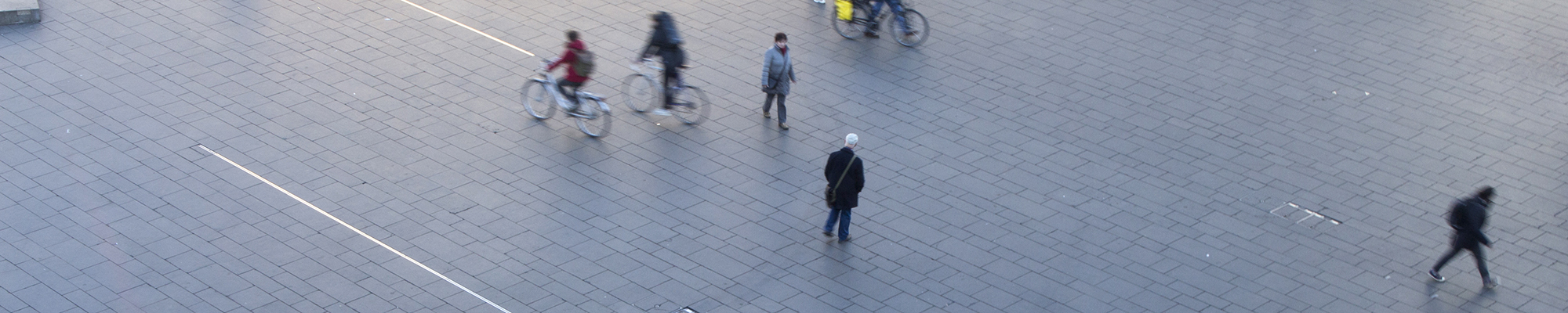 Vereinzelte Menschen auf dem Marktplatz in Halle, Fußgänger sowie Radfahrer. Sie alle gehen in verschiedene Richtungen.