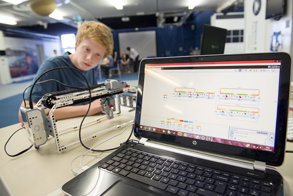 Ein Junge programmiert eine Maschine mit Hilfe einer Software, eventuell Raspberry Pi.