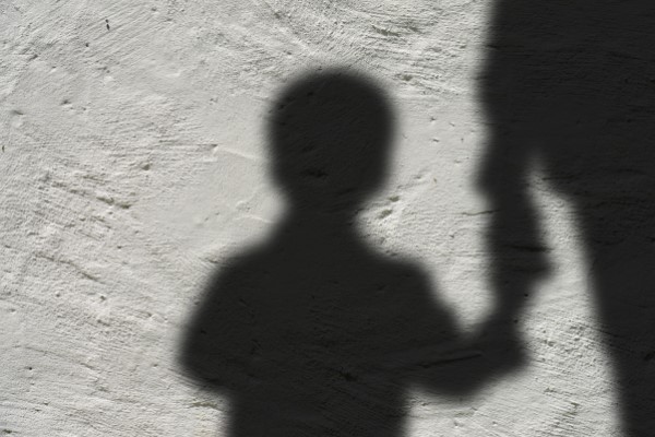 Schatten eines Kindes, welches an die Hand genommen wird von einer größeren Person