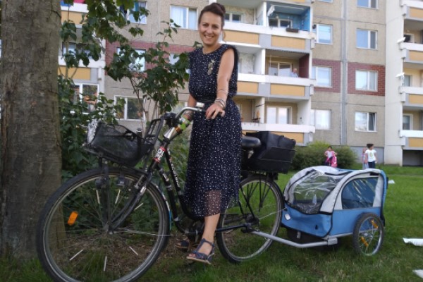 Stadträtin Dörte Jacobi auf ihrem Fahrrad vor einem Wohnhaus in Heide-Nord