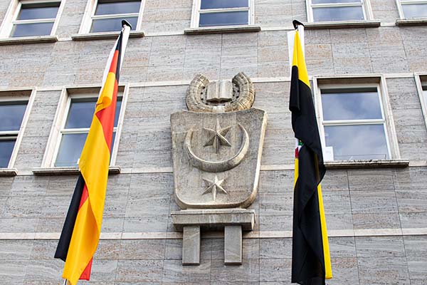 Stadtwappen an der Fassade des Ratshofs, links davon die deutsche Flagge, rechts davon die Flagge des Landes Sachsen-Anhalt