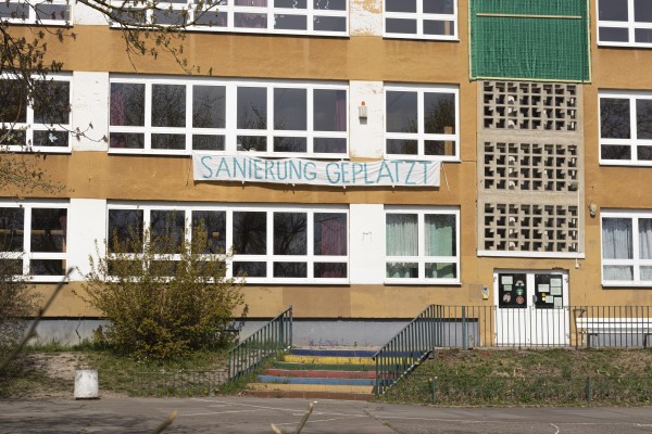 Fassade des Schulgebäudes Grundschule Otfried Preußler mit eine Spruchband auf dem steht "Sanierung geplatzt"