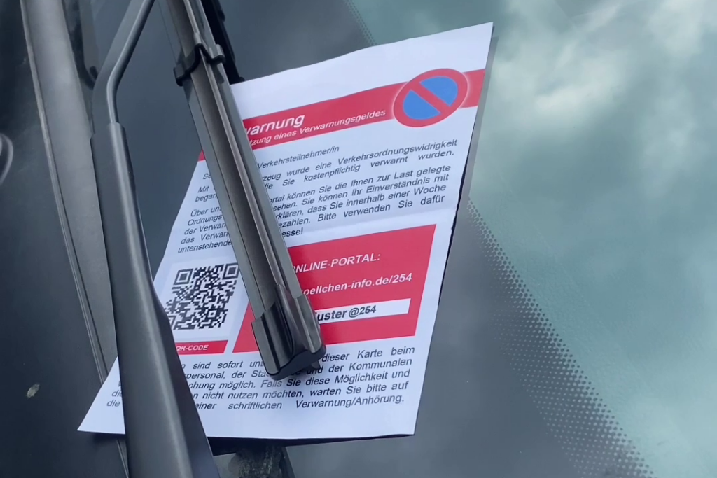 Ein Strafzettel mit QR-Code hinter einem Scheibenwischer